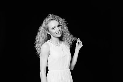 Portrait of a smiling young woman against black background