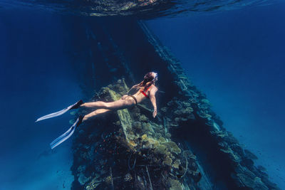 Woman exploring shipwreck swimming undersea
