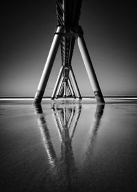 Metallic structure at beach against sky at night