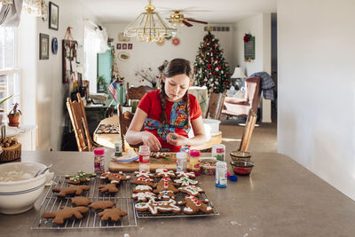 Girl sitting at kitchen counter decorating christmas cookies