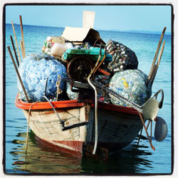 Fishing boats moored in sea against sky