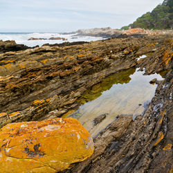 Rock formation on beach against sky