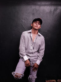 Portrait of young man standing against wall