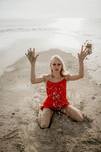 Portrait of young woman sitting on sand at beach