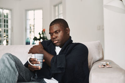 Young man sitting on sofa at home