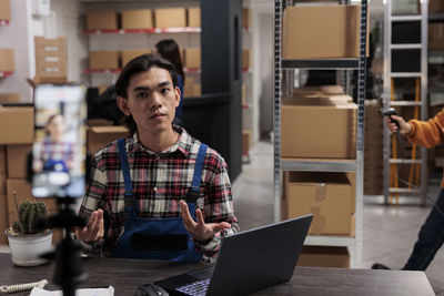 Portrait of young man using laptop while standing in factory