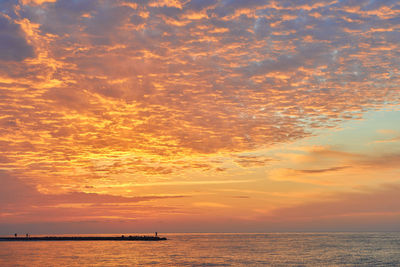 Scenic view of sea against dramatic sky during sunset