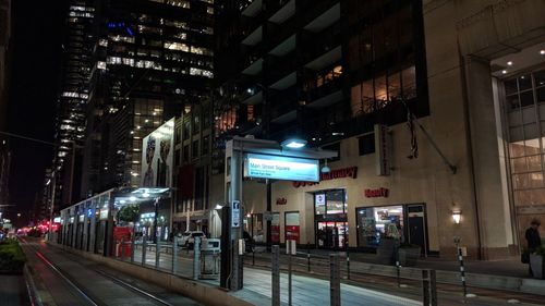 Illuminated street amidst buildings in city at night