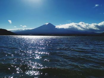 Scenic view of sea and mountains against blue sky