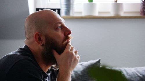 Side view of bearded bald man looking away at home