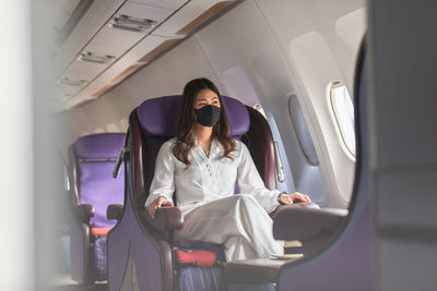 Beautiful woman wearing mask sitting at corporate jet