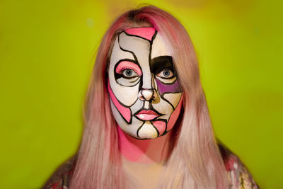Close-up portrait of woman with face paint against green background