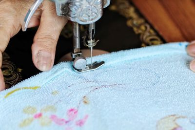 Cropped hand of tailor using sewing machine