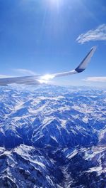 Aerial view of aircraft wing over landscape against blue sky