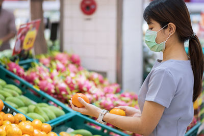 Side view of woman wearing flu mask standing in market
