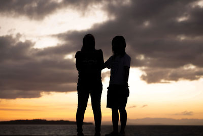 Silhouette couple standing against sky during sunset