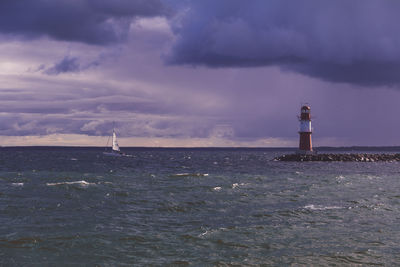 Lighthouse by sea against sky