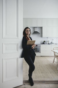 Portrait of confident businesswoman standing at doorway in home office