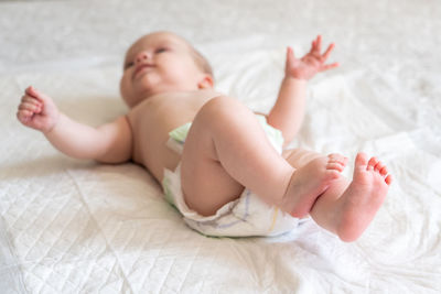 Portrait of shirtless baby boy lying on bed at home