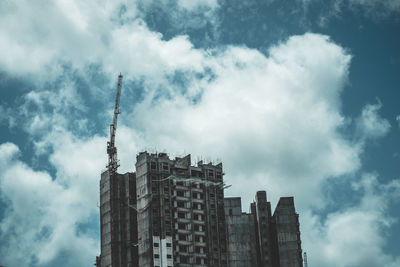 Low angle view of skyscrapers against cloudy sky