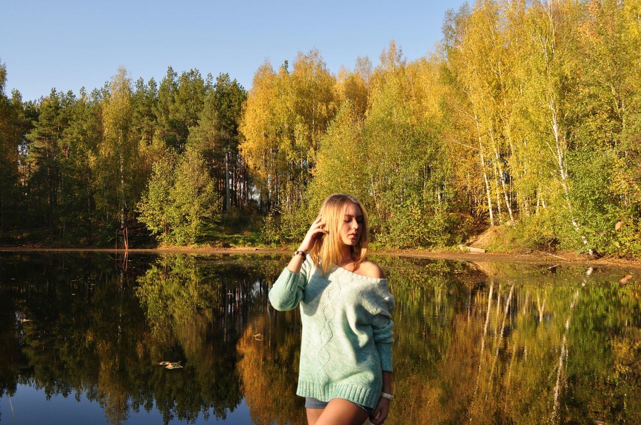 tree, person, water, lifestyles, lake, young adult, casual clothing, leisure activity, standing, portrait, looking at camera, three quarter length, smiling, reflection, tranquility, nature, front view, young women