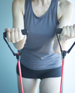 Midsection of woman stretching resistance band in gym