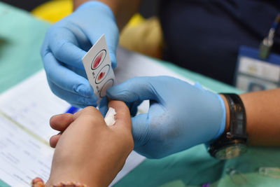 Midsection of pathologist taking blood sample on person