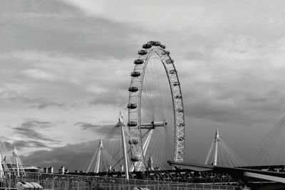 London eye by bridge against sky