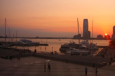 Boats moored at harbor during sunset