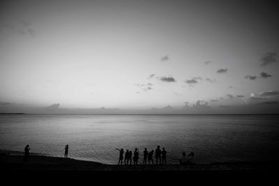 Silhouette people at beach against sky