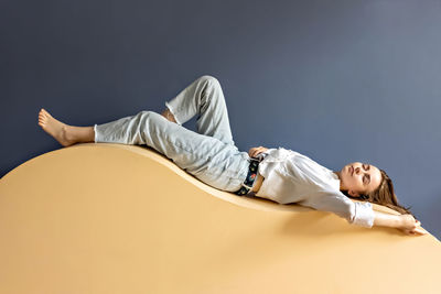 Portrait of a young woman lying on a geometric sand-colored couch.abstract.