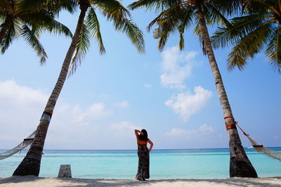 Rear view of woman standing sea against sky