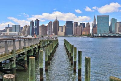 Bridge over river by buildings in city against sky