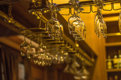 Low angle view of wineglasses hanging in shelf