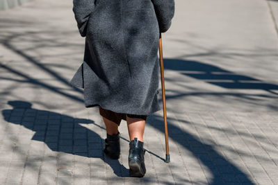 Low section of woman with cane walking on footpath