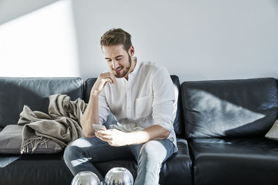 Smiling man sitting on couch looking at cell phone