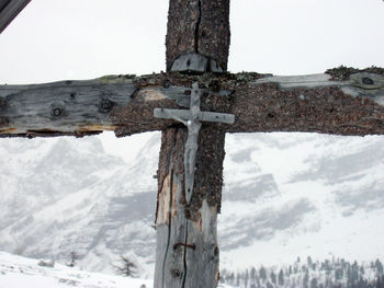 Low angle view of cross on snow against sky