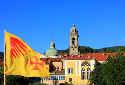 Flag by building against clear blue sky