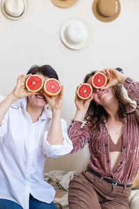 Cheerful women grapefruits against wall