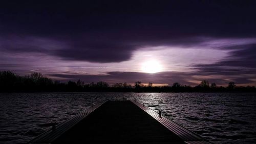 Pier on sea against cloudy sky