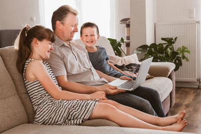 Video conference. social media. dad and the children are sitting in the living room and calling mom