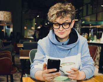 Woman using mobile phone at cafe