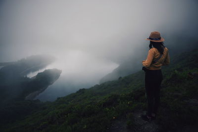 Woman standing on mountain during foggy weather