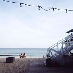 People sitting on beach against clear sky