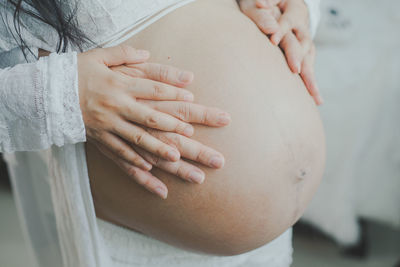 Cropped hand touching pregnant woman stomach 