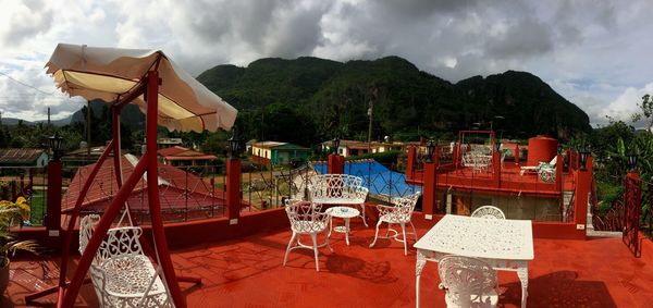 Chairs and table on mountain against sky