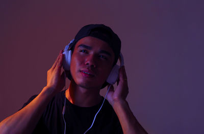 Neon light portrait of a man wearing headphones, listening to music