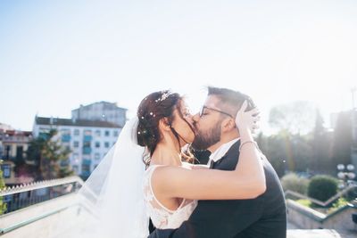 Close-up of couple kissing in city against sky