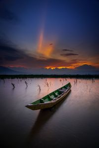 Boat moored on lake against sky during sunset