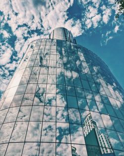 Low angle view of skyscrapers against cloudy sky